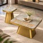 Modern marble centre table set with grey gold veined rectangular tops and tapered metallic bases in a sunlit interior.