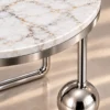 Close-up of white marble tabletop with gold grey veining and reflective silver stainless steel sphere base