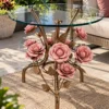 Gold floral glass side table with pink rose sculpture beside a cream sofa in a bright garden-facing lounge