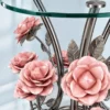 Close-up of pink sculptural metal roses and polished silver floral stems beneath a round glass side table