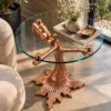 Rose gold tree branch glass side table with decorative bear sculpture displayed beside a cream accent chair