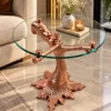 Round glass luxury side table with rose gold bear and tree branch base styled beside a beige sofa
