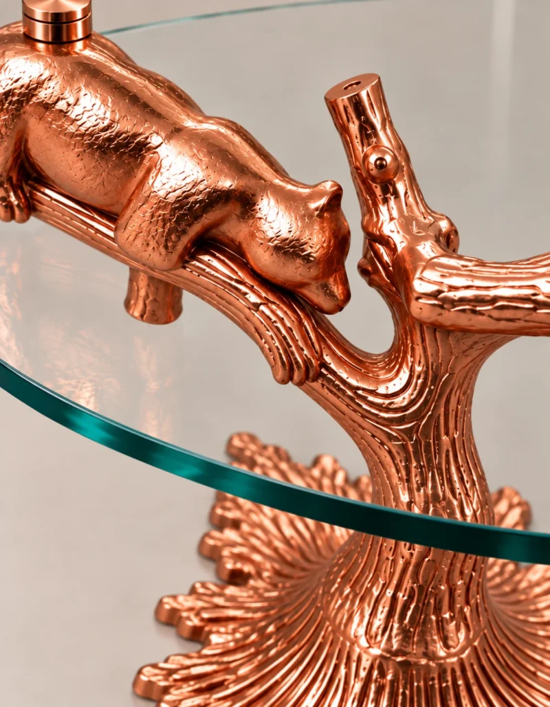 Close-up of resting bear sculpture and textured rose gold branches beneath round glass side table