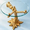 Gold tree branch glass side table with round transparent top and decorative sculptural pedestal on blue background
