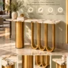 Velora Luxe gold loop console table with white marble top, cylindrical stainless steel pedestal and three U-shaped gold supports.