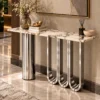 Angled view of a designer white marble console table with stainless steel cylinder and three sculptural loop legs.