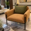 Caramel fabric accent chair with olive-green back cushion and black stainless steel legs in a contemporary luxury interior.