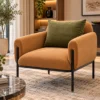 Designer caramel-tan accent chair with textured fabric upholstery, olive-green cushion and black metal legs in a luxury living room.
