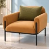 Luxury caramel upholstered lounge chair with olive-green back cushion and black stainless steel frame against a pale blue wall.