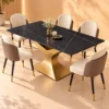 Luxury black marble dining table with gold curved pedestal and five cream upholstered chairs in a warm modern dining room.