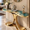 Teal marble console table with sweeping gold dual-wing pedestal beneath a round mirror in a luxury foyer.