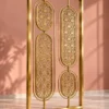 Angled view of gold stainless steel room divider with floral oval lattice panels