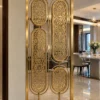Modern gold room divider with four oval floral panels beside dining room