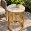 Round gold marble side table with circular lattice shelf displayed beside patio seating and green plants