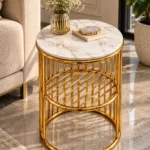 Designer round marble side table with gold stainless steel lattice shelf placed next to a luxury sofa