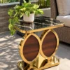Black marble and gold side table with walnut-look dual oval supports styled beside an outdoor patio sofa.