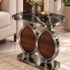 Luxury black marble side table with gun matel-finish dual oval frame and walnut-look panels positioned beside a beige sofa.